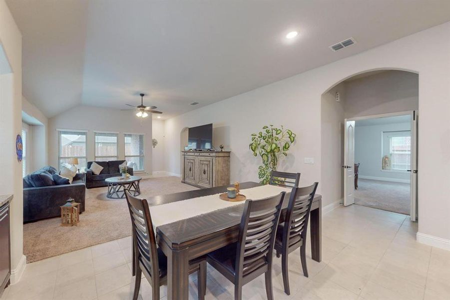 Dining area featuring lofted ceiling, light carpet, and ceiling fan