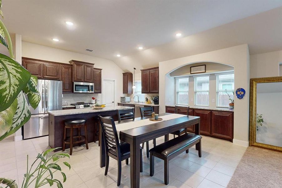 Dining space featuring lofted ceiling, sink, and light tile patterned floors