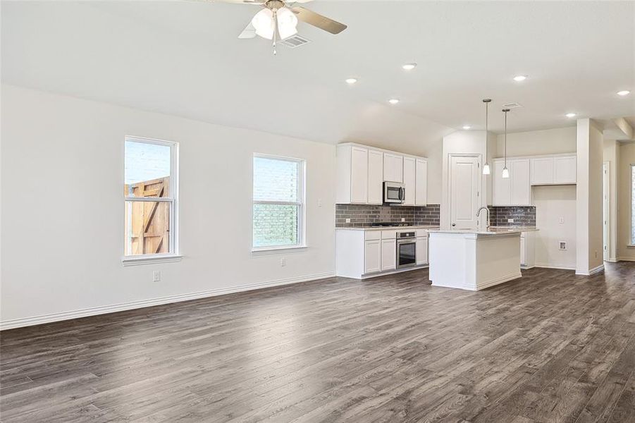 Kitchen featuring decorative light fixtures, dark hardwood / wood-style flooring, an island with sink, ceiling fan, and appliances with stainless steel finishes