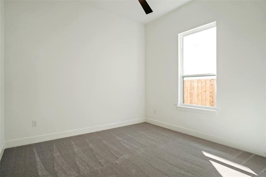 Empty room featuring ceiling fan, carpet flooring, and a wealth of natural light