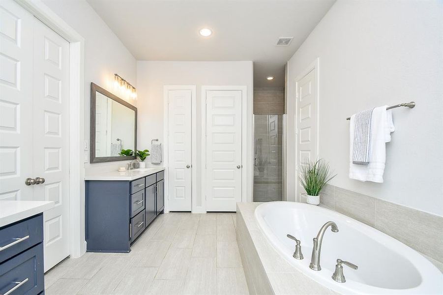 The primary modern, bright bathroom features a large built-in bathtub with tile surround, a separate walk-in shower with glass doors, 2 walk-in closets, 2 separate vanities and separate toilet room