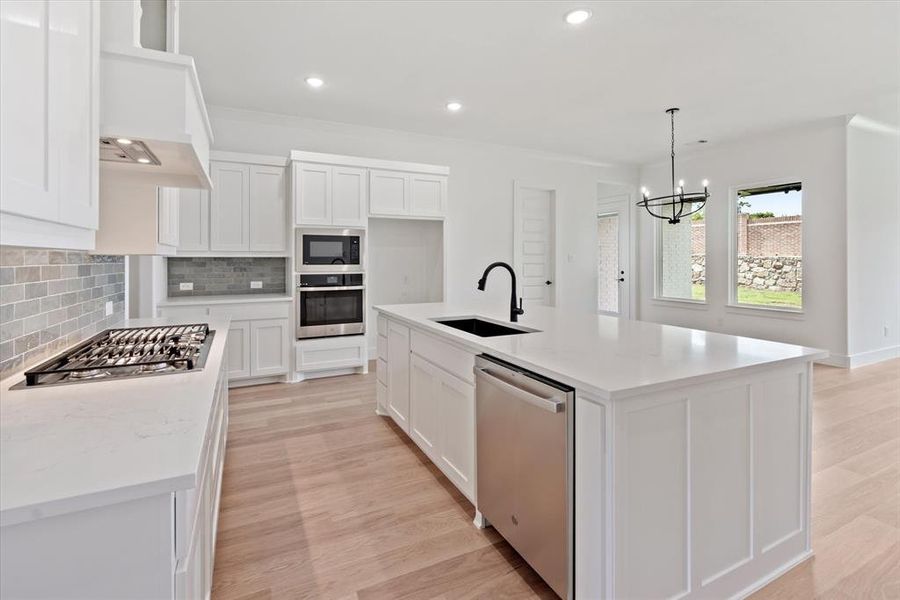 Kitchen with white cabinets, stainless steel appliances, decorative backsplash, and sink