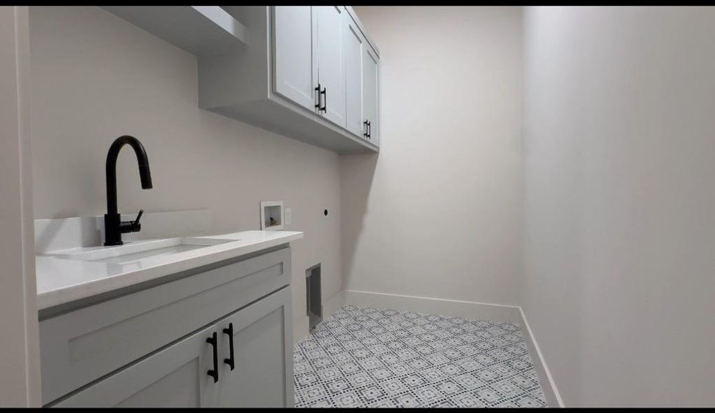 Laundry room featuring light tile patterned flooring, hookup for an electric dryer, sink, cabinets, and hookup for a washing machine