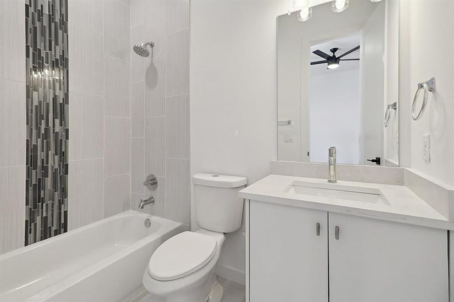 Full bathroom with vanity, tiled shower / bath, ceiling fan, and toilet