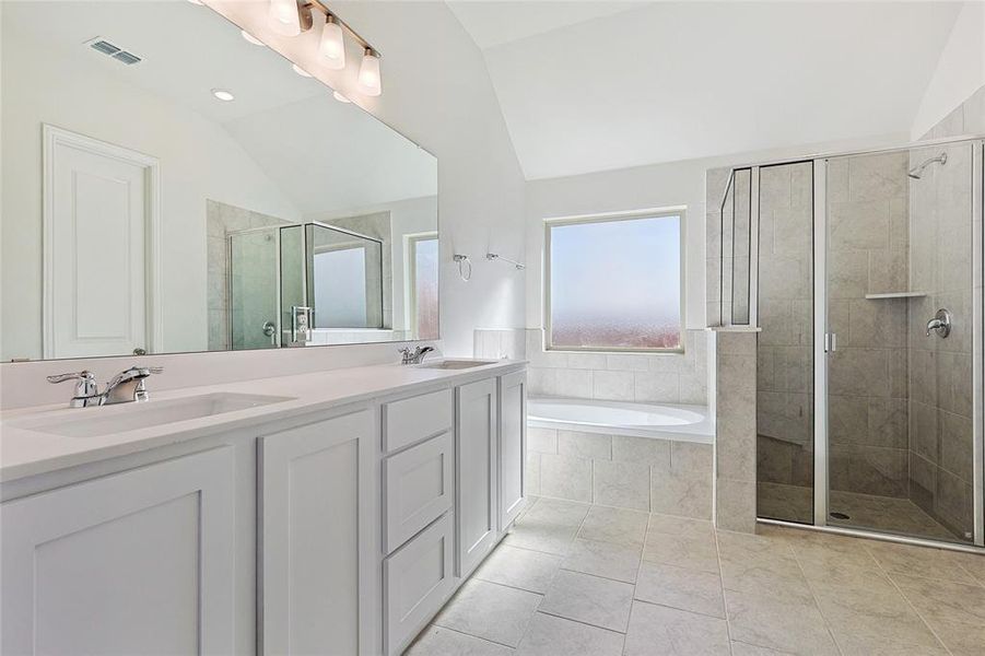 Bathroom with independent shower and bath, lofted ceiling, vanity, and tile patterned floors