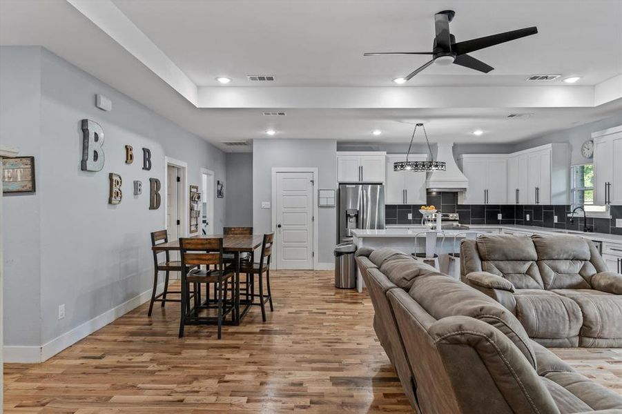 Living room with ceiling fan, light hardwood, and sink