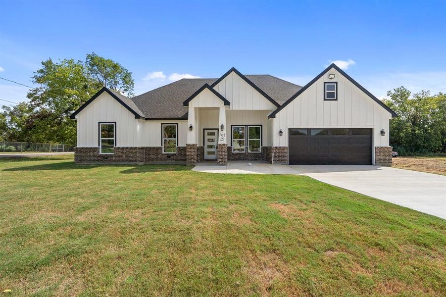 Modern inspired farmhouse with a garage and a front yard