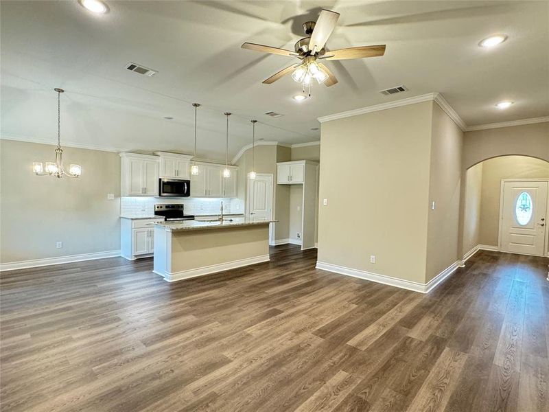 Kitchen with stainless steel appliances, a kitchen island with sink, white cabinetry, ceiling fan with notable chandelier, and dark wood-type flooring