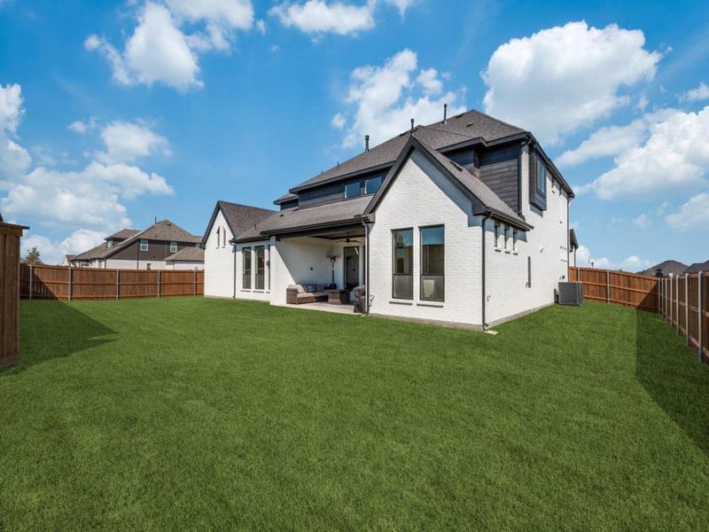 Rear view of property featuring a patio area, central AC unit, and a lawn