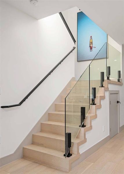 The modern glass stair railing enhances the contemporary aesthetic of the home's interior.