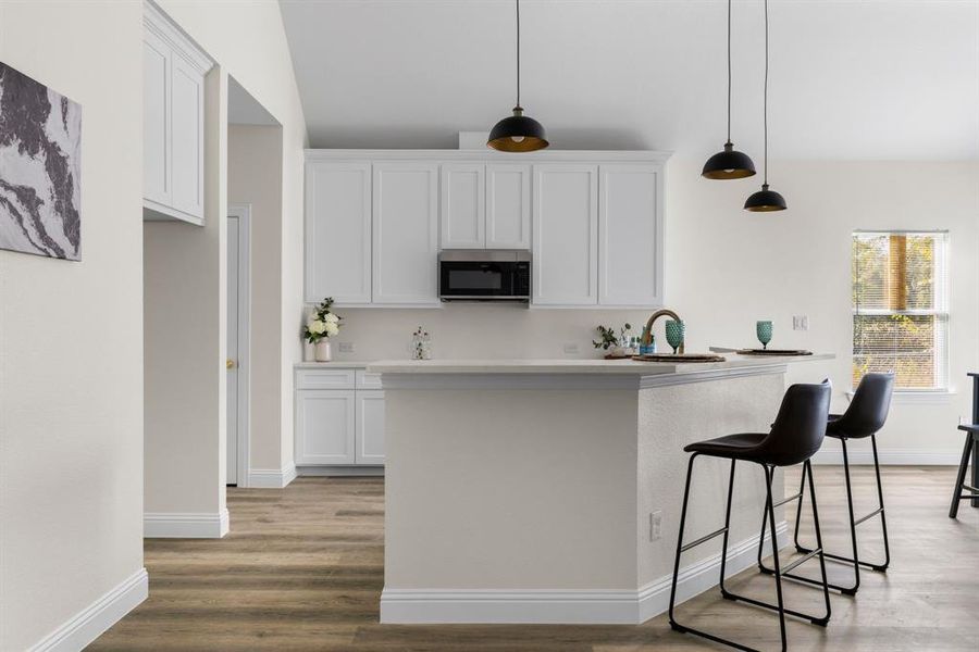 Kitchen with sink, light wood-type flooring, pendant lighting, white cabinets, and a breakfast bar area