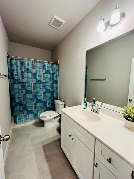 Bathroom with tile patterned floors, a shower with curtain, toilet, and vanity