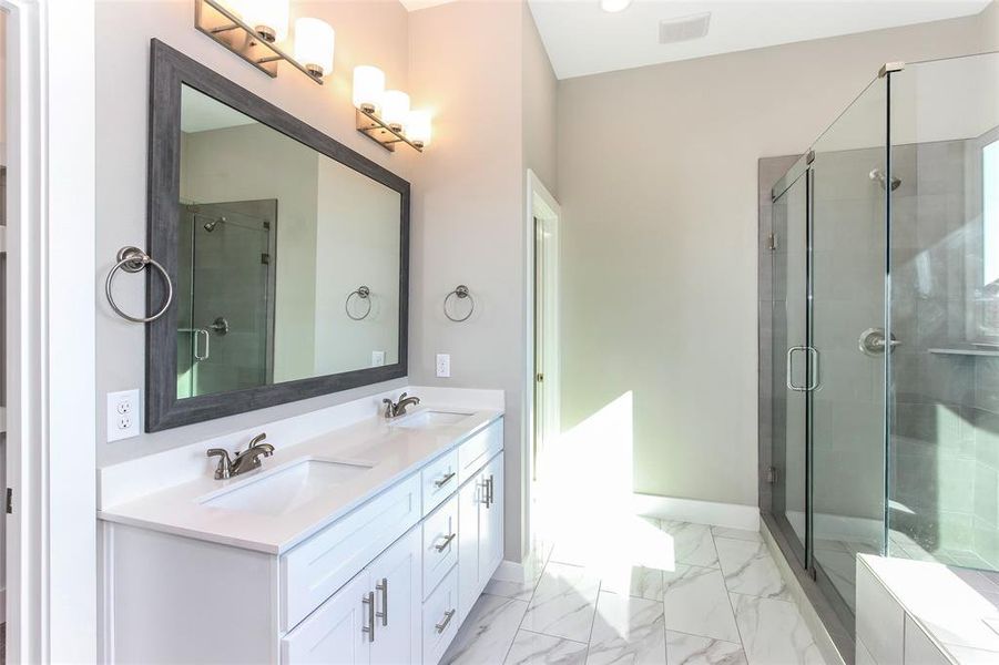 Bathroom featuring a shower with shower door and vanity