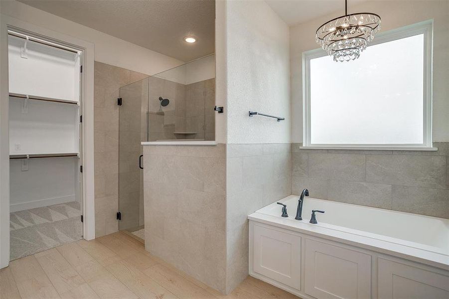 Bathroom featuring hardwood / wood-style flooring, a notable chandelier, and separate shower and tub