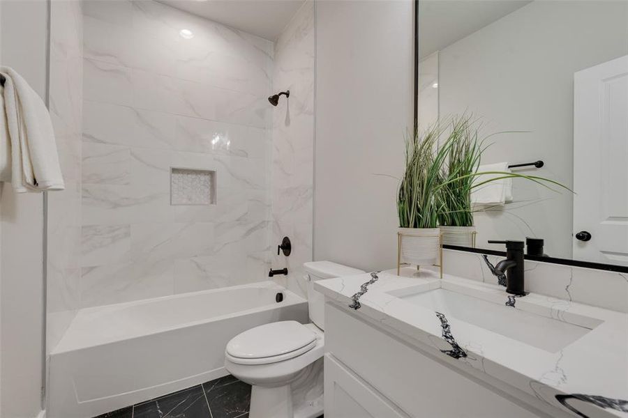 Full bathroom with tiled shower / bath combo, vanity, tile patterned flooring, and toilet