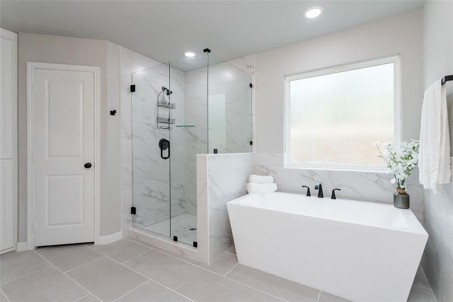 Bathroom with tile patterned flooring, tile walls, and separate shower and tub