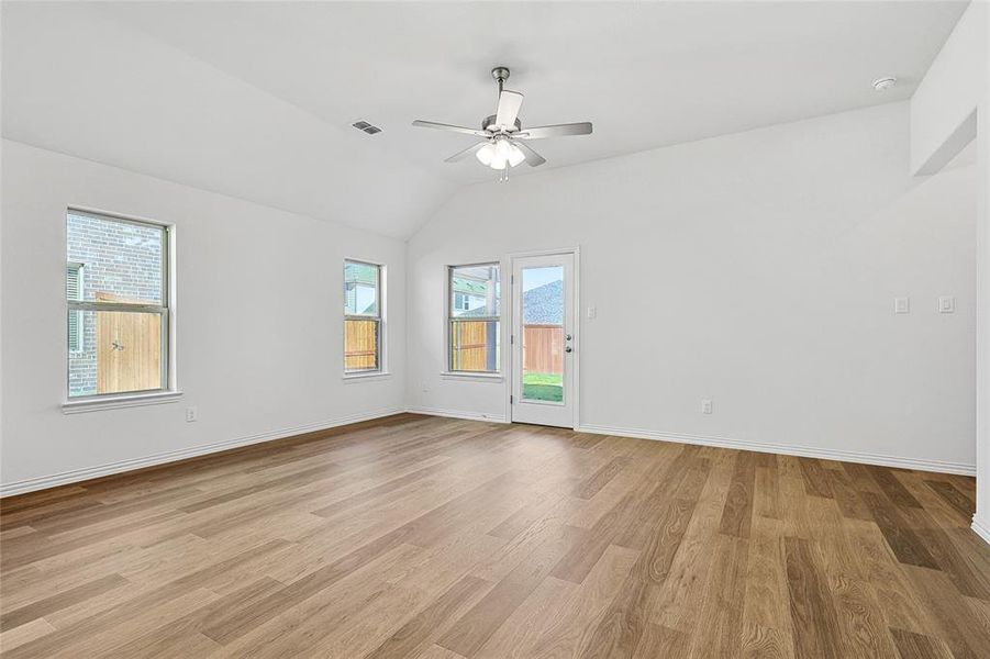 Spare room featuring light wood-type flooring, vaulted ceiling, and ceiling fan