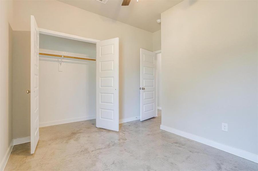 Unfurnished bedroom featuring concrete floors, a closet, and ceiling fan