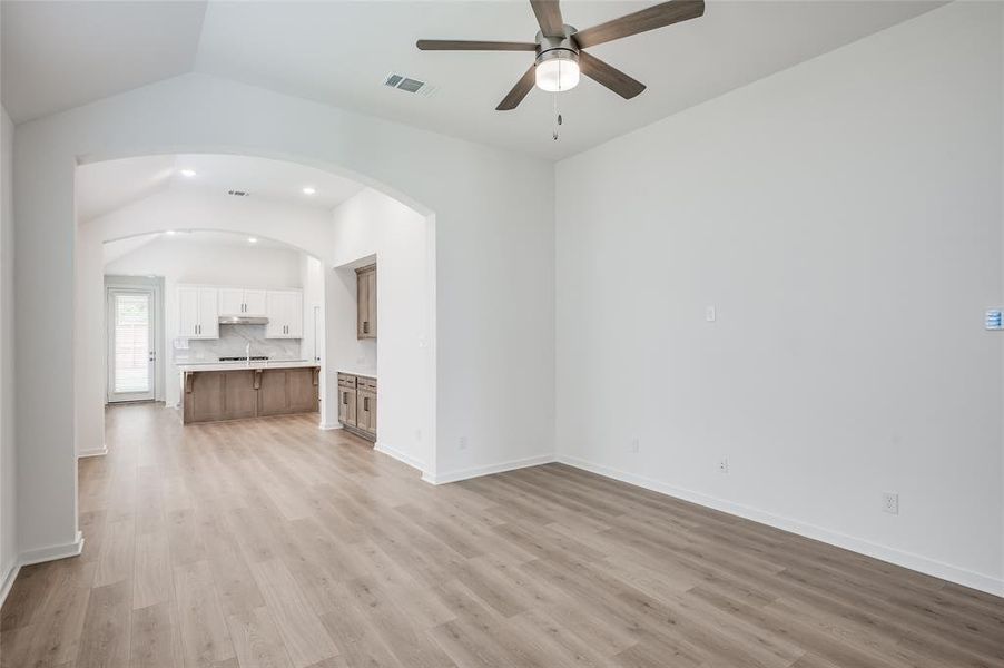 Family room with tall ceilings and arched entry into dining room.