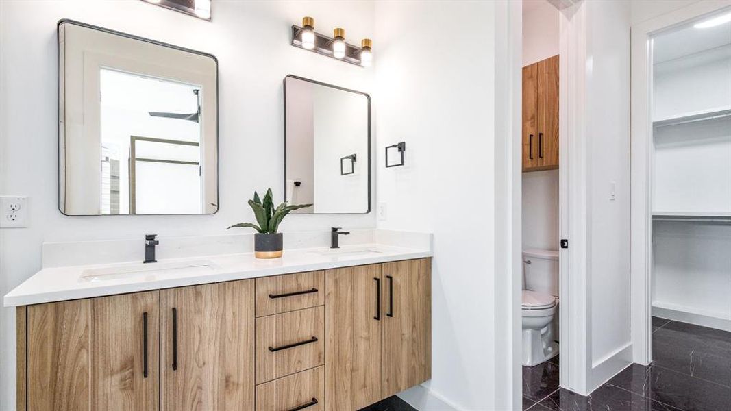 Bathroom featuring tile floors, dual sinks, oversized vanity, and toilet