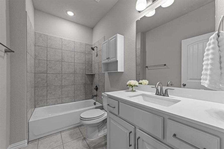 Full bathroom with tile patterned floors, tiled shower / bath, toilet, and vanity