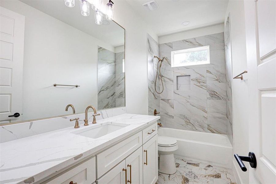 Full bathroom with tiled shower / bath combo, vanity, tile patterned floors, and toilet