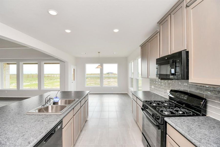 The kitchen features tile floors, black appliances, stainless steel sink, and spacious island.