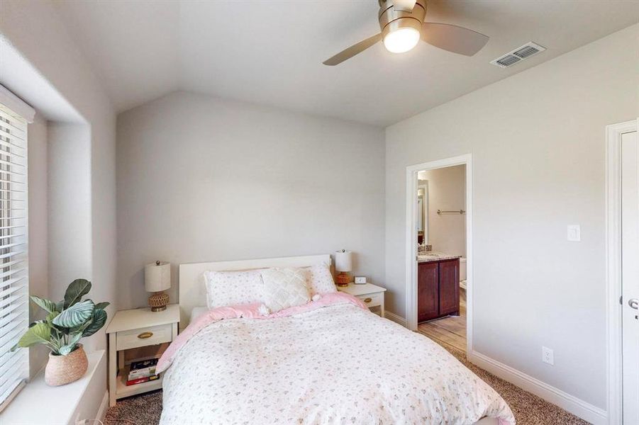 Carpeted bedroom featuring ensuite bath, ceiling fan, and lofted ceiling