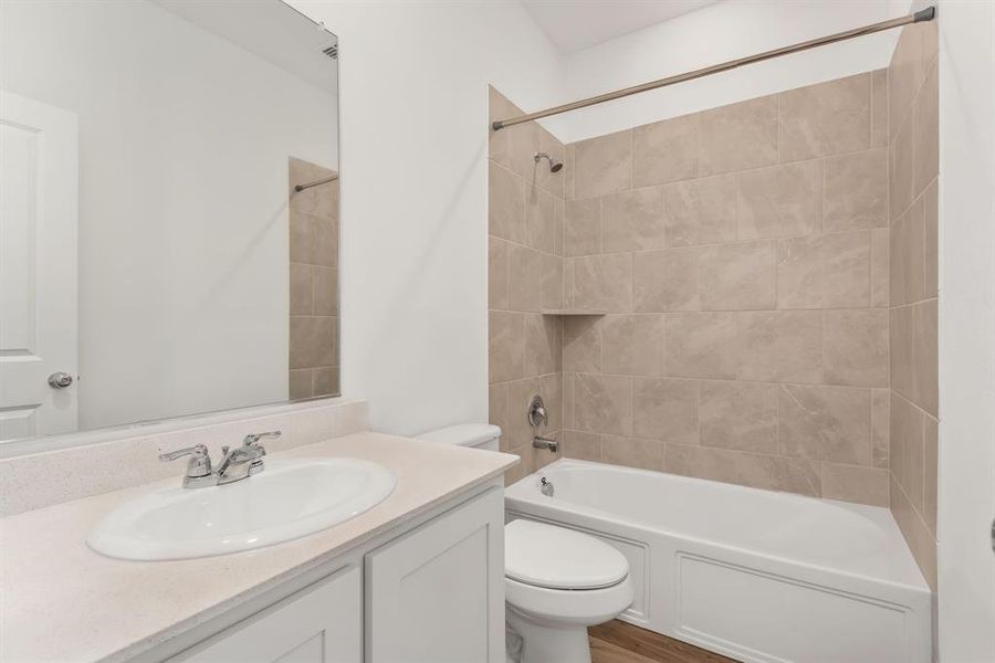 Full bathroom featuring tiled shower / bath, hardwood / wood-style flooring, toilet, and vanity