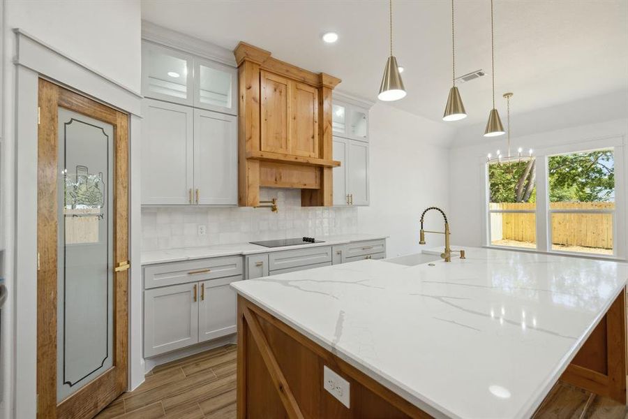 Kitchen with sink, an island with sink, wood-type flooring, and black electric cooktop