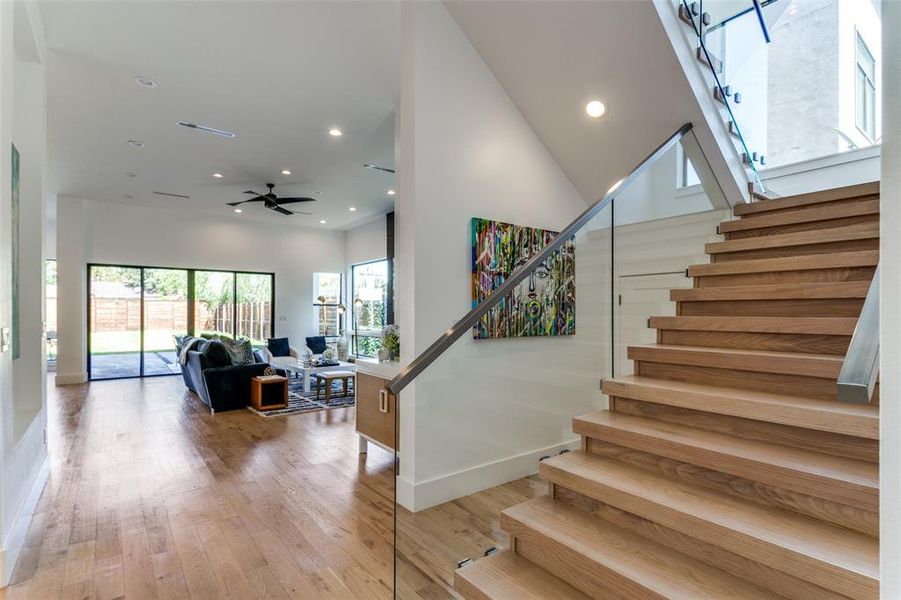 Stairs with a towering ceiling, hardwood / wood-style flooring, and ceiling fan