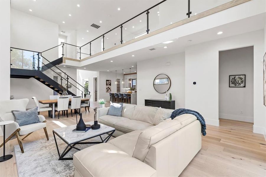 Living room with light hardwood / wood-style flooring and a high ceiling