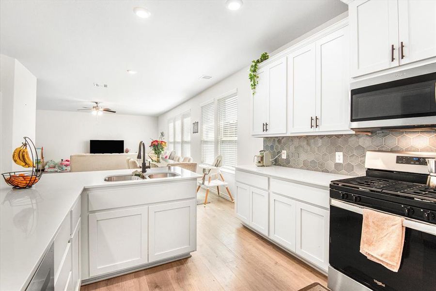 Kitchen with sink, white cabinets, light hardwood / wood-style flooring, appliances with stainless steel finishes, and ceiling fan