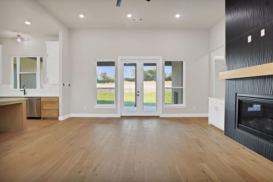 Unfurnished living room with a large fireplace, light hardwood / wood-style floors, and ceiling fan