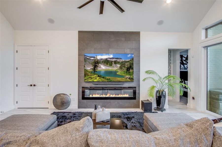 Living room with ceiling fan, a tiled fireplace, and tile walls