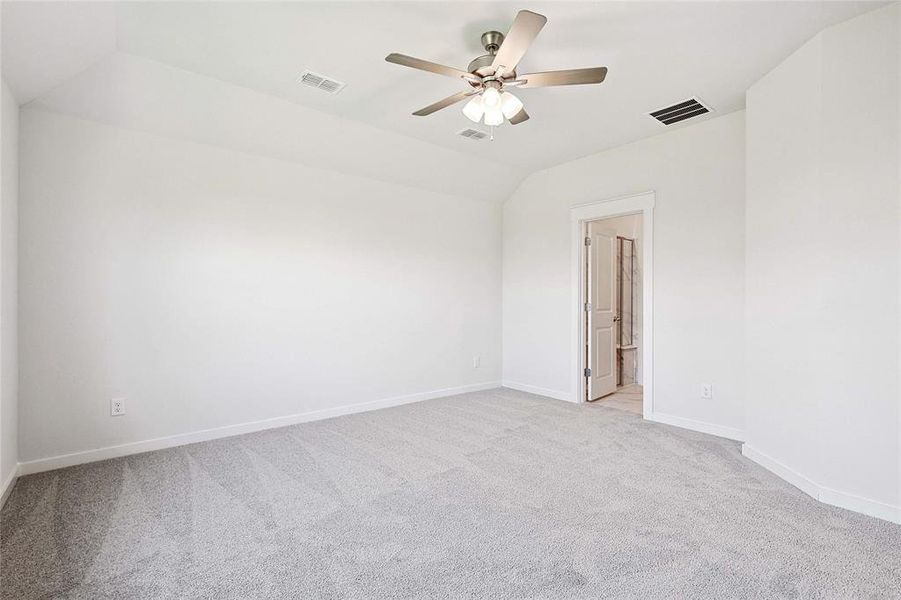 Unfurnished room featuring ceiling fan, lofted ceiling, and light colored carpet