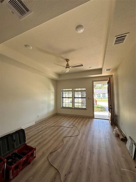 Living room with ceiling fan, tray ceiling, Laminate flooring, and a raised ceiling