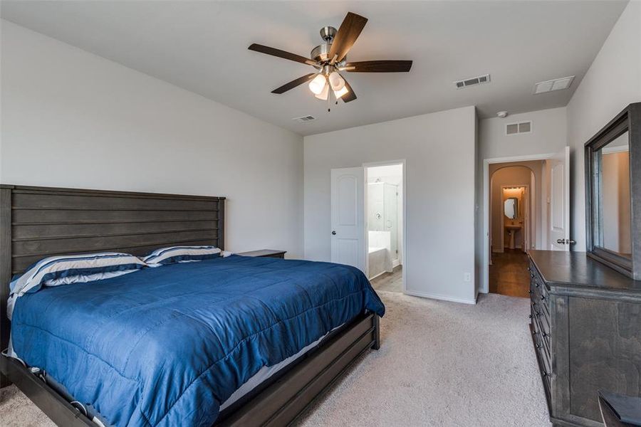 Bedroom with connected bathroom, ceiling fan, and light colored carpet