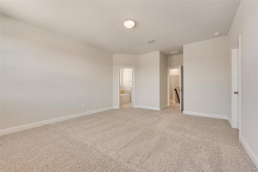 Unfurnished bedroom with ensuite bath and light carpet