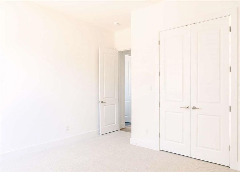 Unfurnished bedroom with light colored carpet and a closet