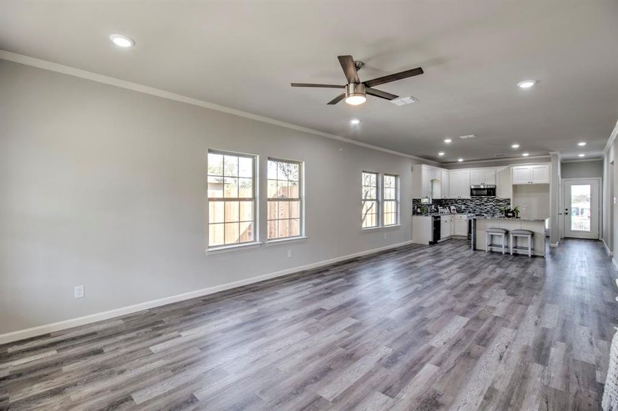 Unfurnished living room featuring light hardwood / wood-style flooring, ceiling fan, and crown molding