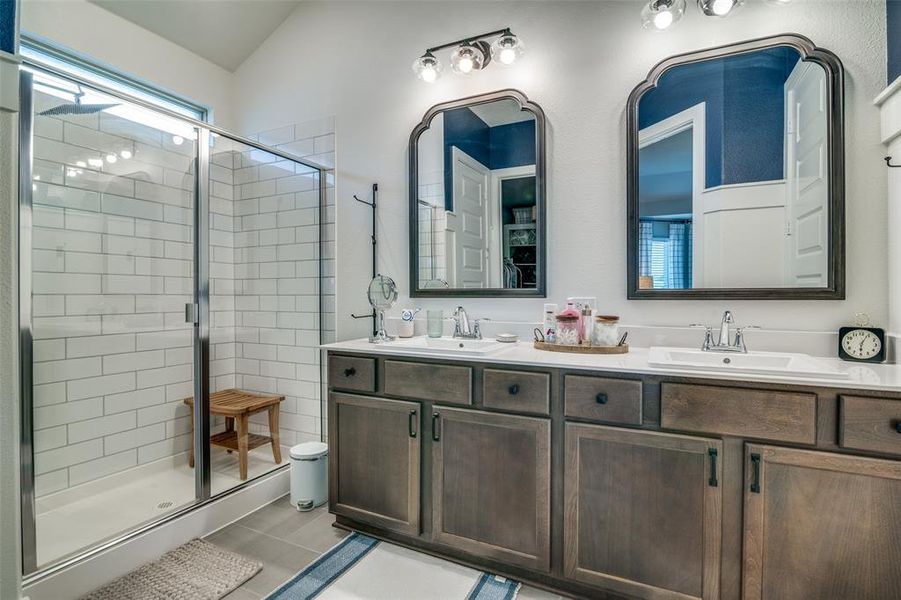 Bathroom featuring walk in shower, lofted ceiling, vanity, and tile patterned floors