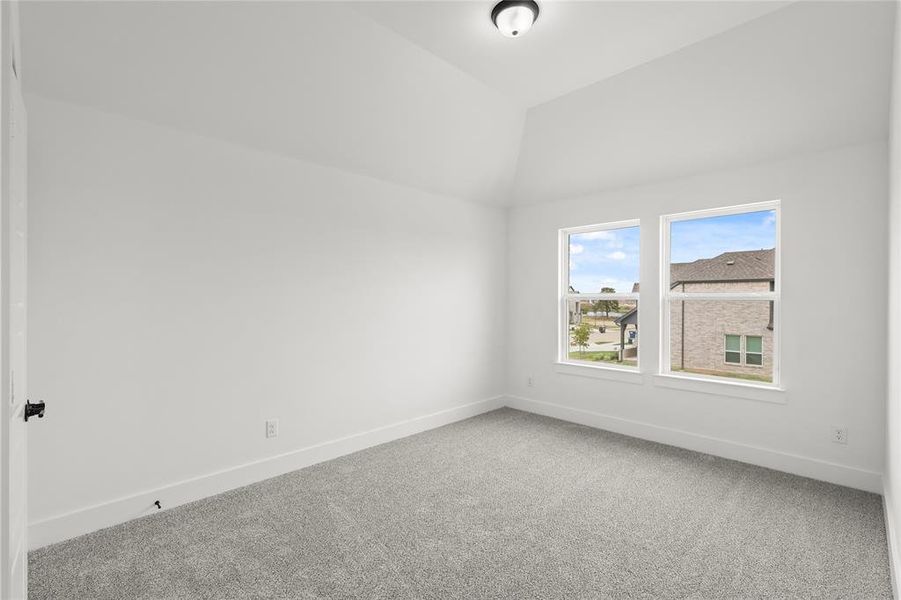 Unfurnished room featuring carpet and vaulted ceiling