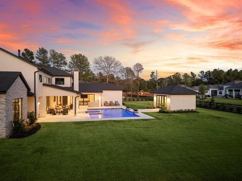 This perspective of the backyard showcases the pool house as well as the generous greenspace of the property's grounds. Meticulously landscaped and thoughtfully designed, it forms the ideal outdoor sanctuary.