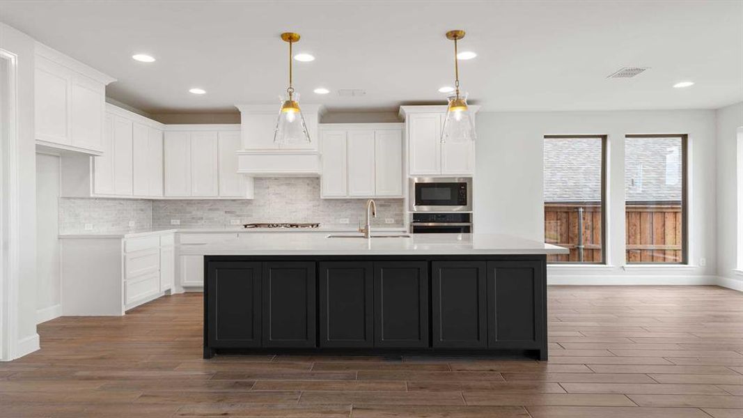 Kitchen with a kitchen island with sink, white cabinetry, dark wood-type flooring, and stainless steel appliances