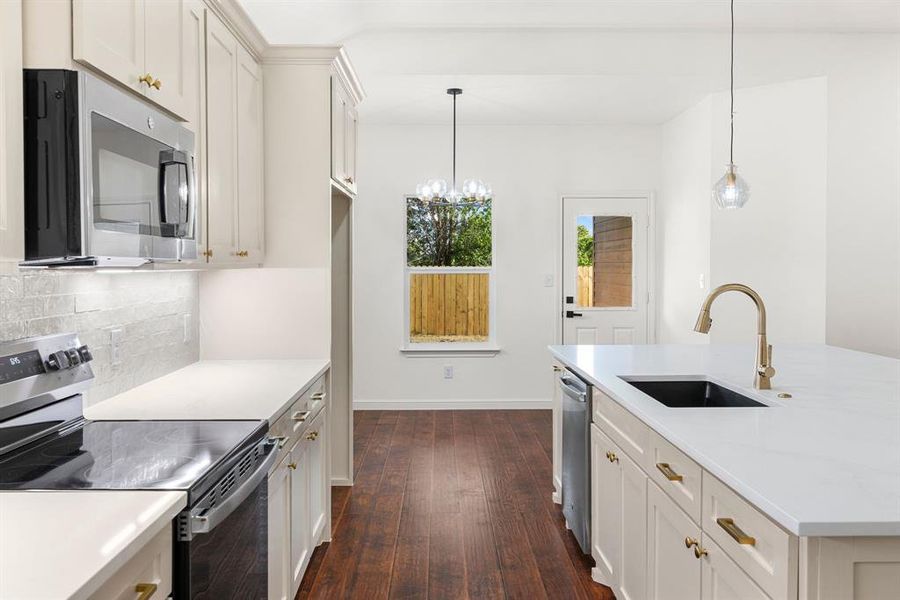 Kitchen with tasteful backsplash, dark hardwood / wood-style flooring, stainless steel appliances, hanging light fixtures, and sink