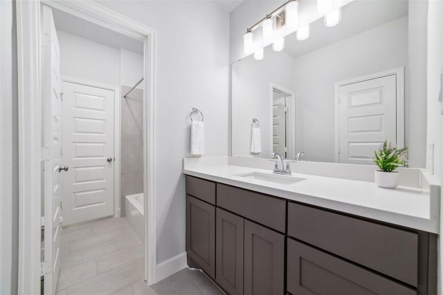 This Jack and Jill Bathroom features two large Quartz vanities, each with a wide mirror and a bath tub shower combo.