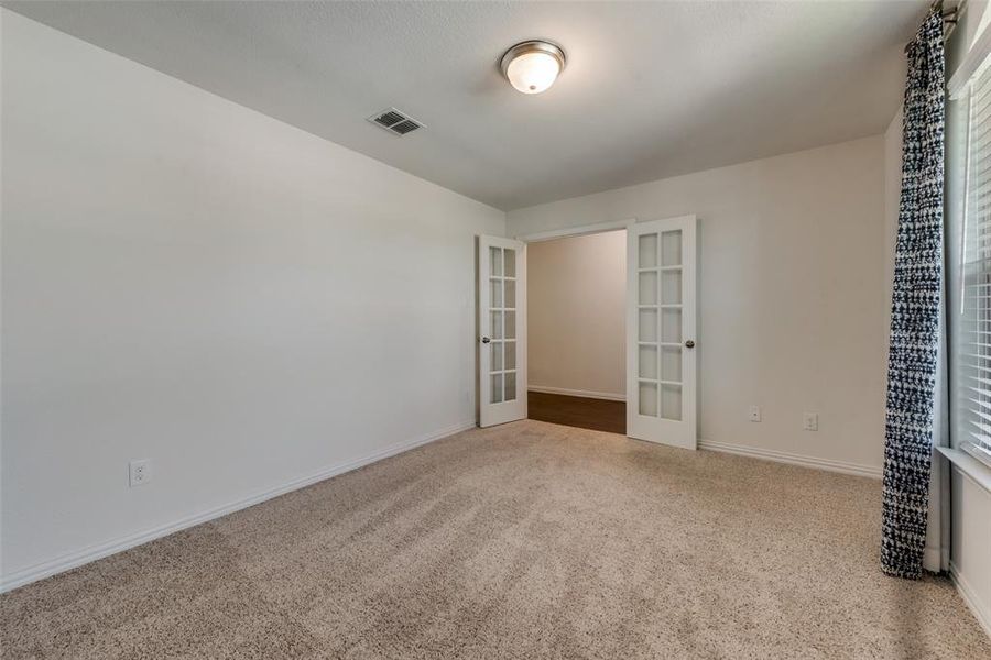 Unfurnished bedroom with french doors and carpet