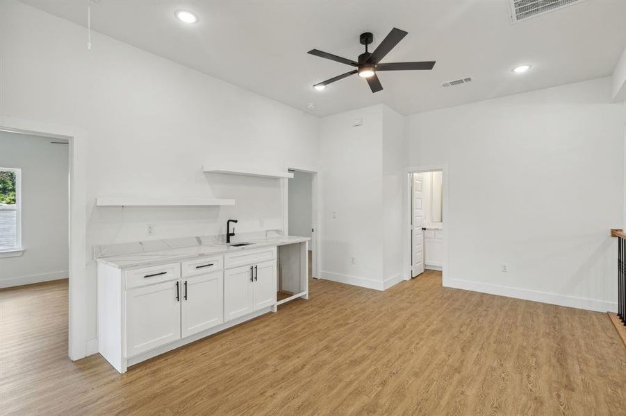 Kitchen featuring sink, ceiling fan, light hardwood / wood-style flooring, and white cabinetry