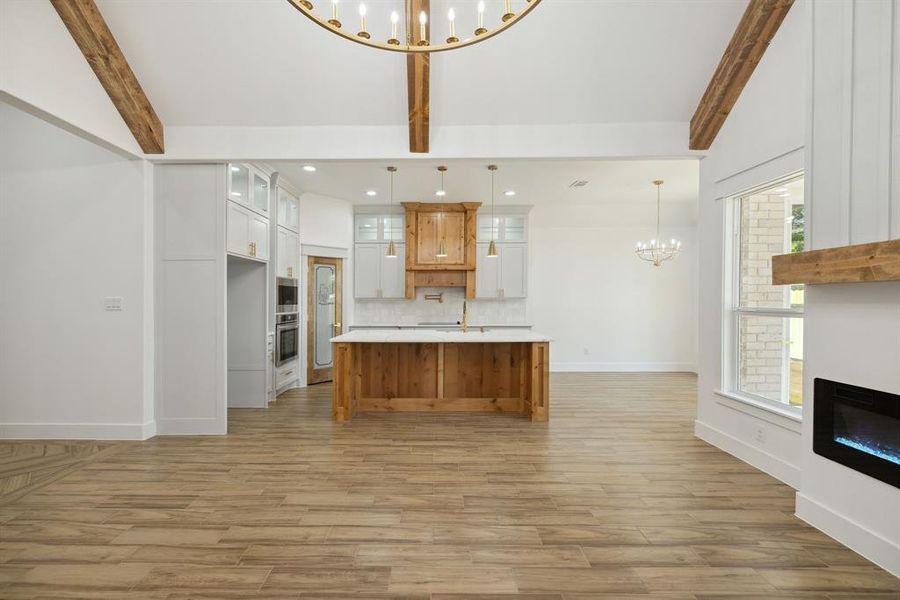 Kitchen with oven, light hardwood / wood-style flooring, hanging light fixtures, a center island, and white cabinetry